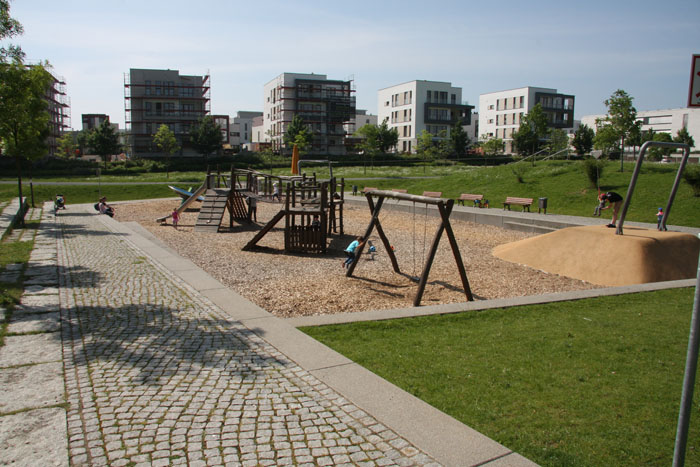 Spielplatz mit Schaukeln im Vordergrund.