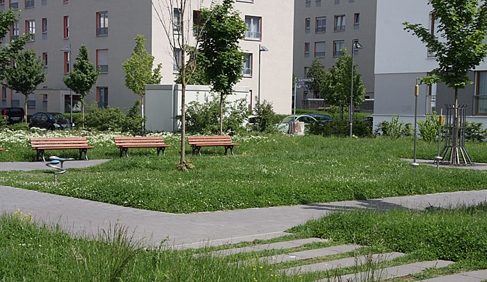 Der Platz vor dem Ki.Bi.Z-Kindergarten. Die Spielgeräte sind am linken und rechten Rand der Wiese zu sehen..